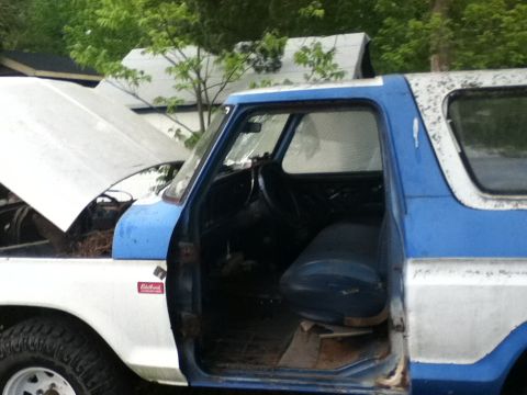 1979 Ford Bronco - This two-tone SUV has its hood up and the driver's door open, revealing the interior.