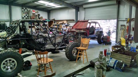 1985 Jeep CJ7 - Two custom off-road vehicles are in various stages of completion inside a workshop.