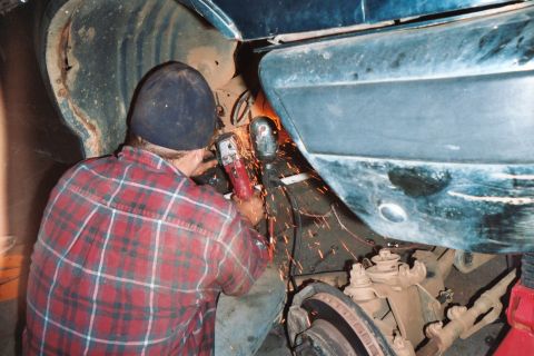 1988 Ford Bronco - A person works on the underside of a vehicle, sparks flying from an angle grinder.