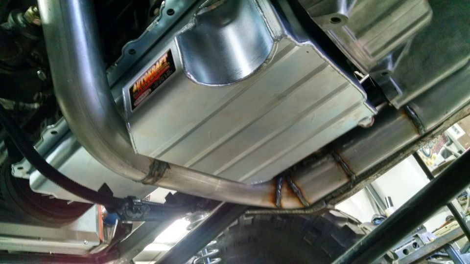 Underbody view of a vehicle showing an aftermarket exhaust system and a polished aluminum oil pan with an "AUTOKRAFT" logo