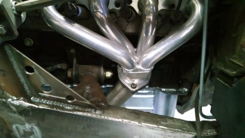 1985 Jeep CJ7 - Shiny exhaust headers are installed on an engine, with visible custom metalwork in the foreground.