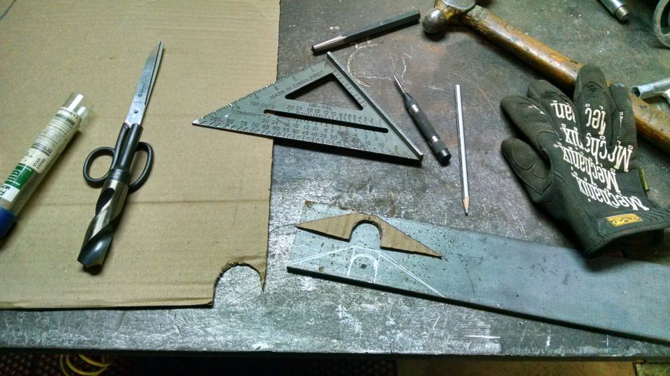 Workbench with drill bit scissors, square, scribe, pencil, hammer, and metal pieces