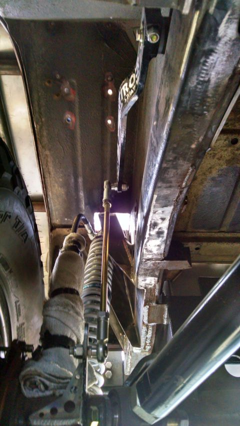 1985 Jeep CJ7 - Close-up of vehicle undercarriage, focusing on suspension parts and frame structure. A TROS branded component is visible.
