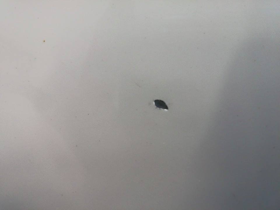 Close-up of a small dent on a car's body panel. Supermotors.net logo visible