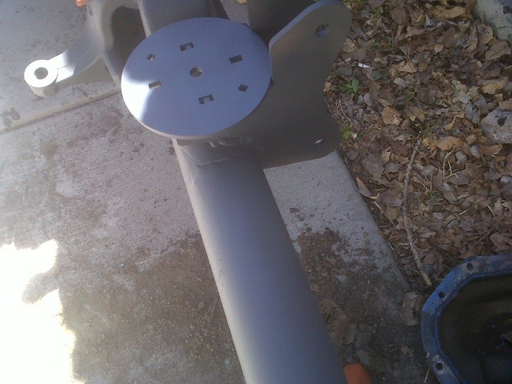 Gray painted axle assembly with a circular mounting plate and multiple bolt holes