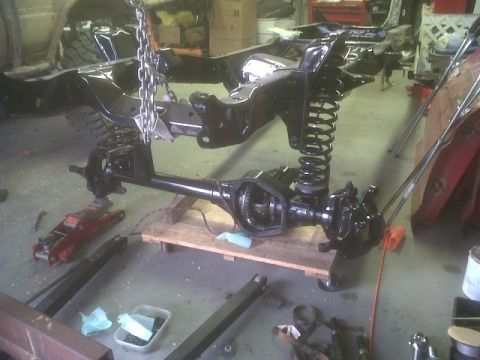 1979 Ford Bronco - Workshop scene shows a vehicle's frame and suspension components being worked on, with various tools and parts scattered around.