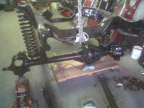 1979 Ford Bronco - Vehicle frame and suspension components are being worked on in a garage setting.