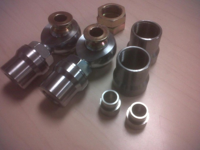 Several metal automotive parts, possibly axle components, laid out on a surface