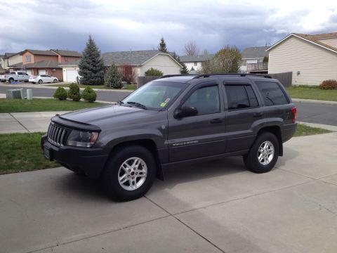 2004 Jeep Grand Cherokee - This 2004 Jeep Grand Cherokee is shown from a three-quarter front view, parked on a concrete driveway in a residential area.
