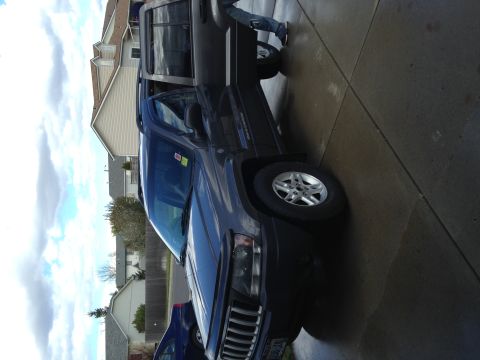 2004 Jeep Grand Cherokee - 2004 Jeep Grand Cherokee parked on a driveway with the driver's side door open.