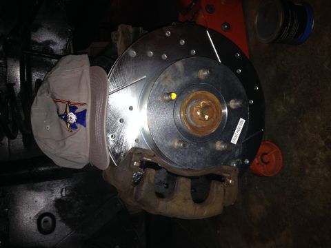 2004 Jeep Grand Cherokee - Close-up of a vehicle's front brake rotor and caliper assembly, with a baseball cap resting on the suspension.