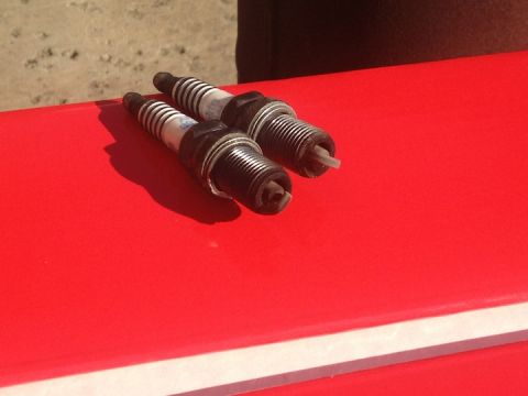 1961 International Scout 800 - Two spark plugs are shown resting on a red surface with a sandy background.