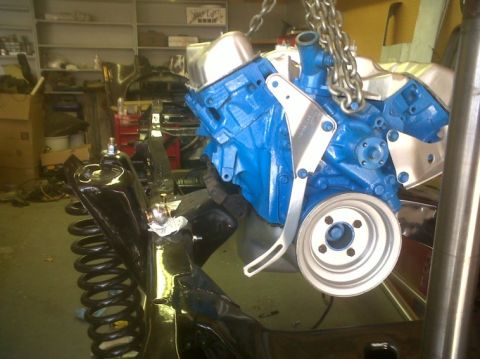 1979 Ford Bronco - A blue engine block is hoisted by chains, showing its pulley and mounting hardware in a garage setting.