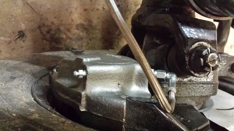 1978 Ford Bronco - Close-up view of a vehicle's brake caliper and associated brake line components.