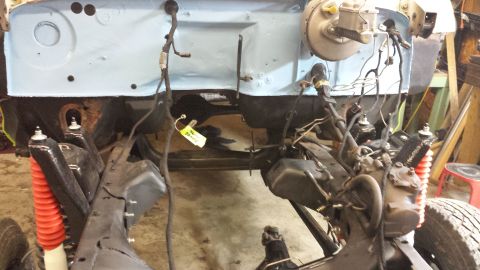 1978 Ford Bronco - The engine bay and chassis of a 1978 Ford Bronco are visible, undergoing restoration work with a yellow tag attached to wiring.