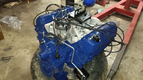 1978 Ford Bronco - A blue V8 engine is shown, resting on a tire with a red engine hoist nearby.