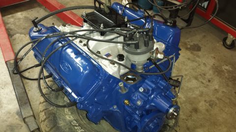 1978 Ford Bronco - A blue Ford V8 engine, likely a replacement or rebuild, sits on a tire in a garage setting.