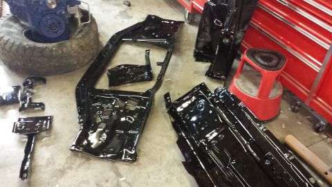 1978 Ford Bronco - Vehicle frame sections and engine block are laid out on the floor, possibly for restoration.