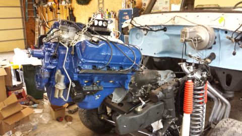 1978 Ford Bronco - Engine installation in progress, showing the blue engine and suspension components within the vehicle's frame.