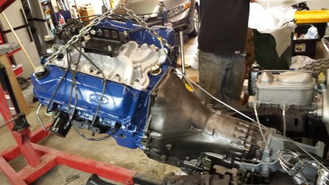 1978 Ford Bronco - Ford V8 engine and transmission assembly suspended by chains, ready for installation.