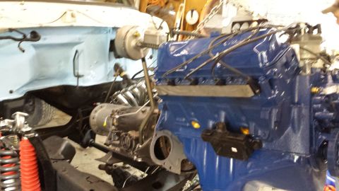 1978 Ford Bronco - The engine is being installed into the vehicle's chassis, showing the engine bay and mechanical components.