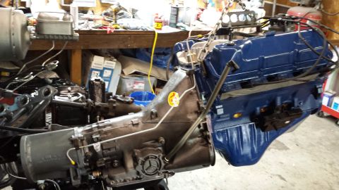 1978 Ford Bronco - Engine and transmission assembly, likely for a Ford vehicle, is being worked on in a garage setting.