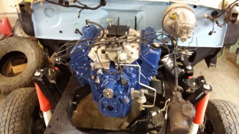 1978 Ford Bronco - The engine bay of a 1978 Ford Bronco is shown, a freshly painted blue engine and bright red shock absorbers.