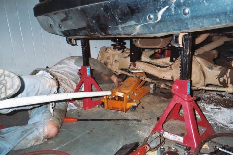 1988 Ford Bronco - A mechanic works on the undercarriage of a vehicle that is raised for service.