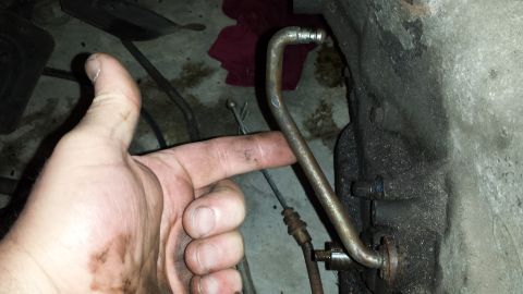 1978 Ford Bronco - Close-up of a metal tube and engine component, with a hand indicating its location.