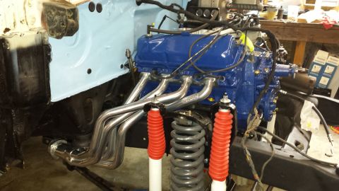 1978 Ford Bronco - A blue Ford V8 engine with chrome exhaust headers is installed in a vehicle chassis. Red shock absorbers and grey coil springs are visible…