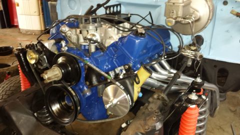 1978 Ford Bronco - The engine bay shows a freshly painted blue engine with new exhaust headers and visible belts and pulleys.