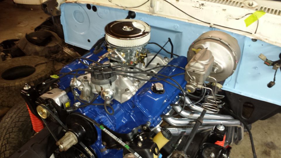 Close-up of a V8 engine with blue valve covers and chrome air cleaner. Brake booster and master cylinder visible