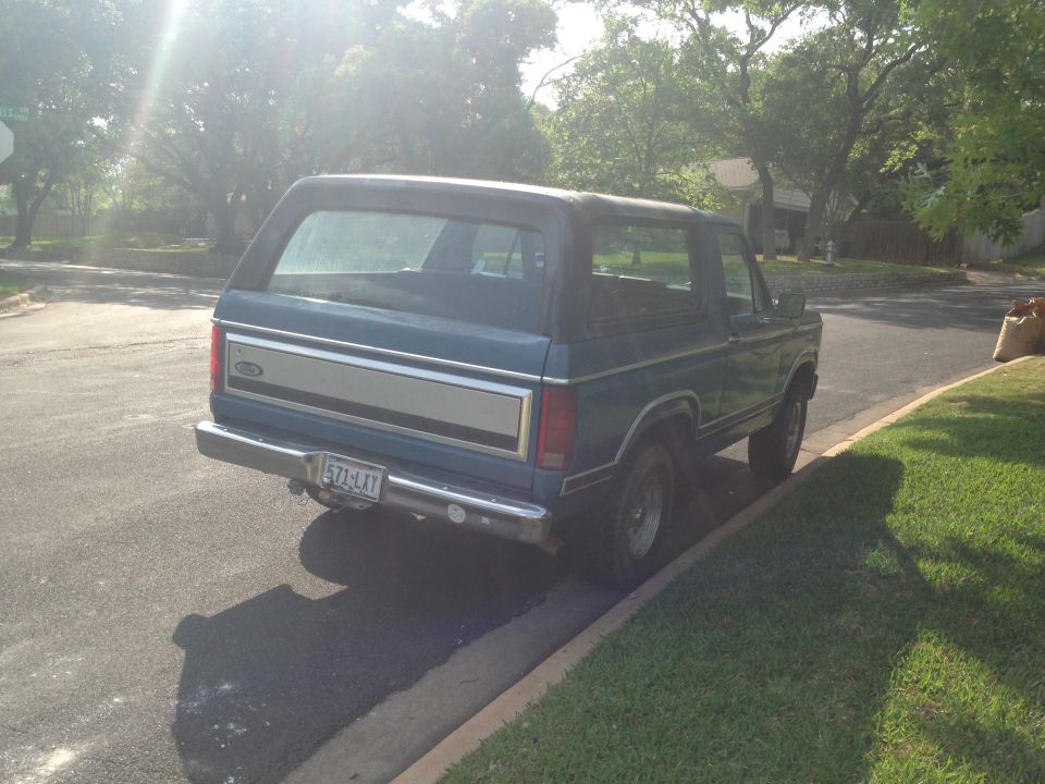 Blue SUV parked curbside, rear view. Chrome bumper, silver trim panel on tailgate, license plate 571-LXY