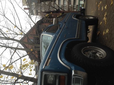 1984 Ford Bronco - A blue Ford Bronco with chrome trim and raised suspension is parked outdoors on a paved surface.