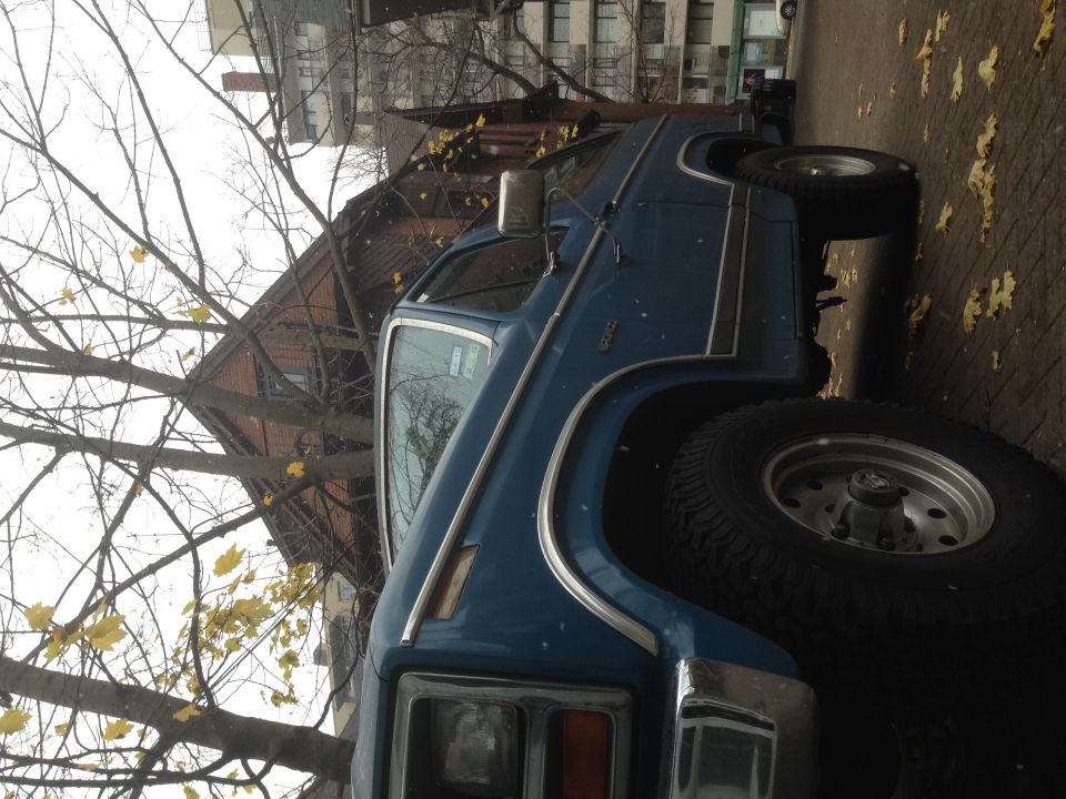 Blue Ford Bronco with chrome trim and raised suspension, seen from the front-right