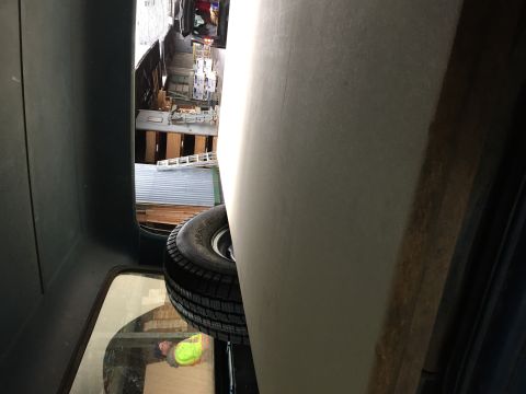 1984 Ford Bronco - Spare tire visible in the cargo area of a vehicle, with a workshop visible through the rear window.