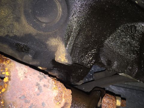 1984 Ford Bronco - Oily engine block casting and rusty exhaust pipe are visible in this close-up shot.
