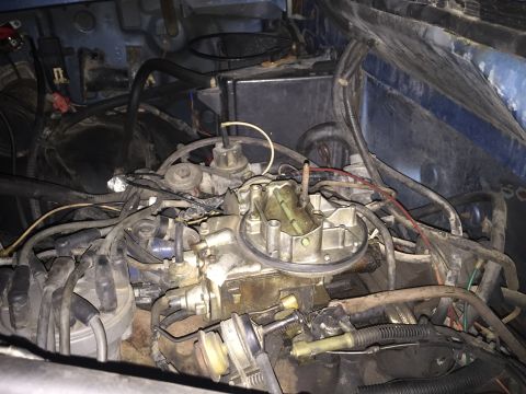 1984 Ford Bronco - Close-up view of the engine bay, focusing on the carburetor and associated wiring and hoses.