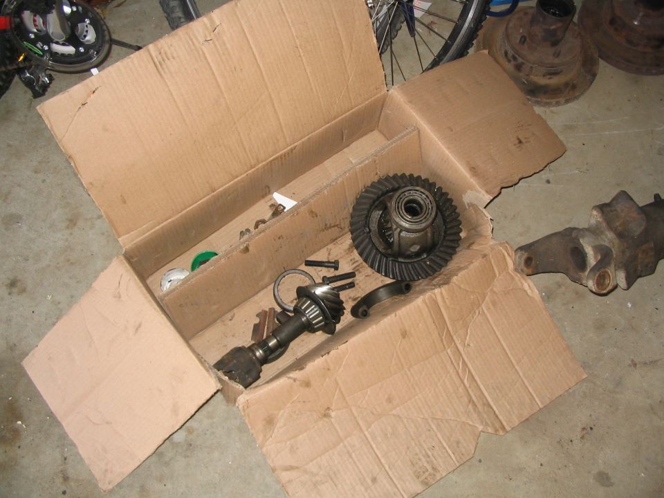 Differential ring and pinion gears in an open cardboard box on a garage floor