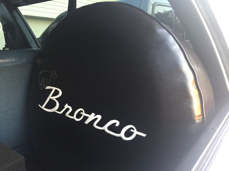 Black spare tire cover with white Bronco logo and text