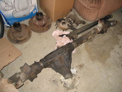 1989 Ford Bronco - Front axle components and brake rotors laid out on the floor.
