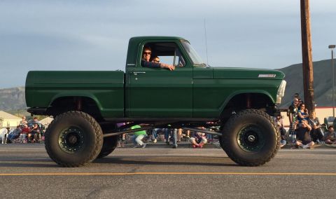 1967 Ford F-250 - This lifted 1967 Ford F-250 pickup truck is participating in a parade with spectators watching.