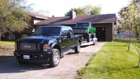 1967 Ford F-250 - A black Ford Super Duty tows a green classic pickup truck on a trailer.