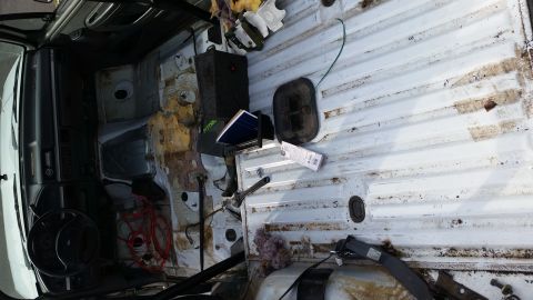 1993 Ford Bronco - The interior of a white van shows a disassembled cargo area with visible rust and exposed wiring.