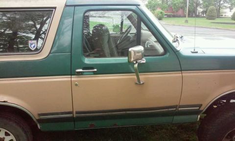 1990 Ford Bronco - Side view of a 1990 Ford Bronco, showing its two-tone paint scheme and door details.