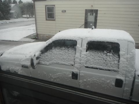 2000 Ford F-250 - A white 2000 Ford F-250 pickup truck is covered in snow, parked in front of a house during winter.