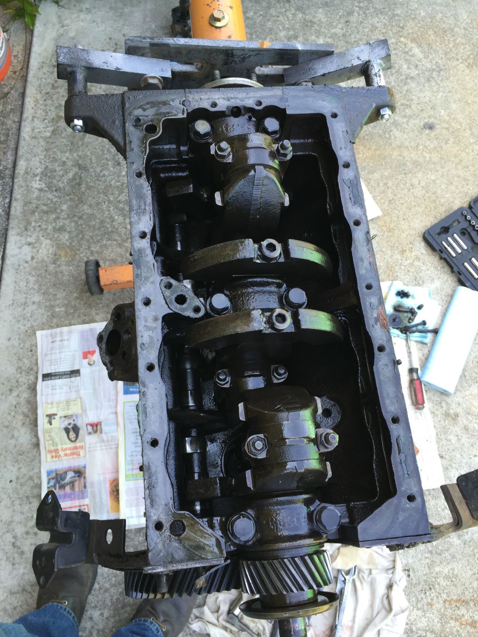 Engine block with crankshaft and gears exposed, resting on an engine stand