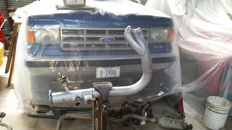 Blue Ford truck front end with "4x4" badge and "Ford" grille, covered in plastic