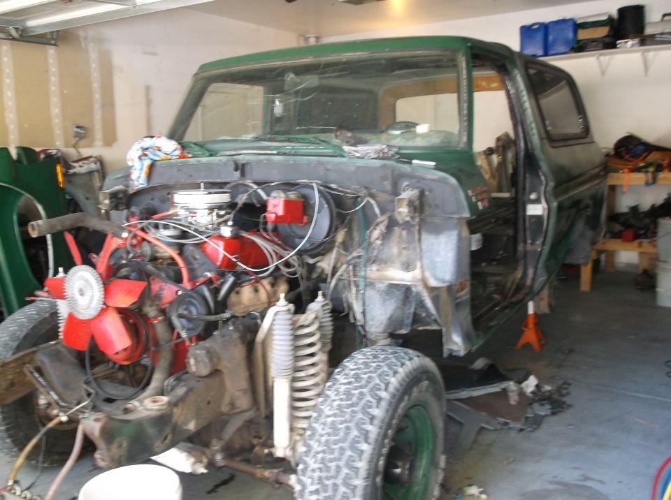 1978 Ford Bronco with front end disassembled in a garage, engine exposed