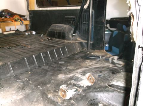 1979 Ford Bronco - The interior of a vehicle appears to be stripped down, with a black floor and visible metal ribs.